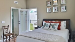 A bedroom with a bed, a chair, a ceiling fan, and framed pictures on the wall. - Fresh look at Shore Pleasure a family fav, steps from beach and downtown (Avila Beach)