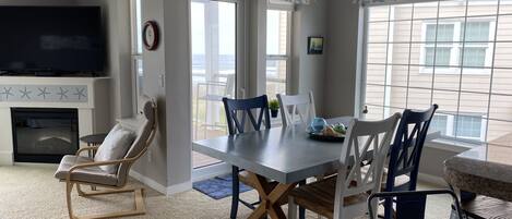 A dining area with a table and chairs, a fireplace, a TV, and a view of the outdoors.
