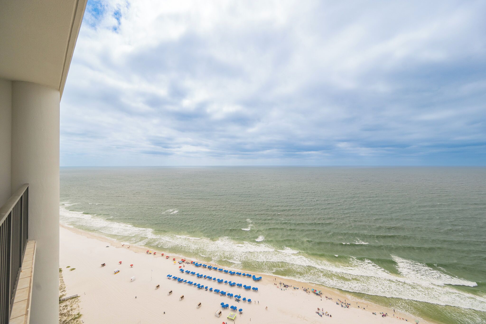 A beach view from a balcony with a clear sky and ocean.