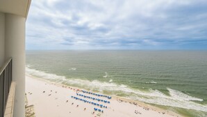 A beach view from a balcony with a clear sky and ocean. - The Oasis at Orange Beach, formerly known as Phoenix West II, Unit 2402 (Orange Beach)