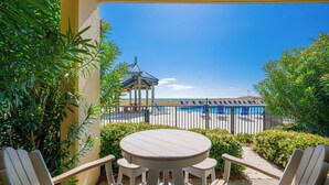 A patio with a round table and chairs, a pool area with lounge chairs, and a view of the beach. - Phoenix V 013 Beachfront 2BR Ground Floor Retreat (Orange Beach)