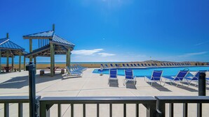 A poolside area with lounge chairs, a pool, and a view of the ocean. - Phoenix V 013 Beachfront 2BR Ground Floor Retreat (Orange Beach)