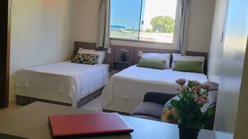 Ein Hotelzimmer mit zwei Betten, einem roten Laptop auf einem Tisch und einer Blumentopf mit Blumen.