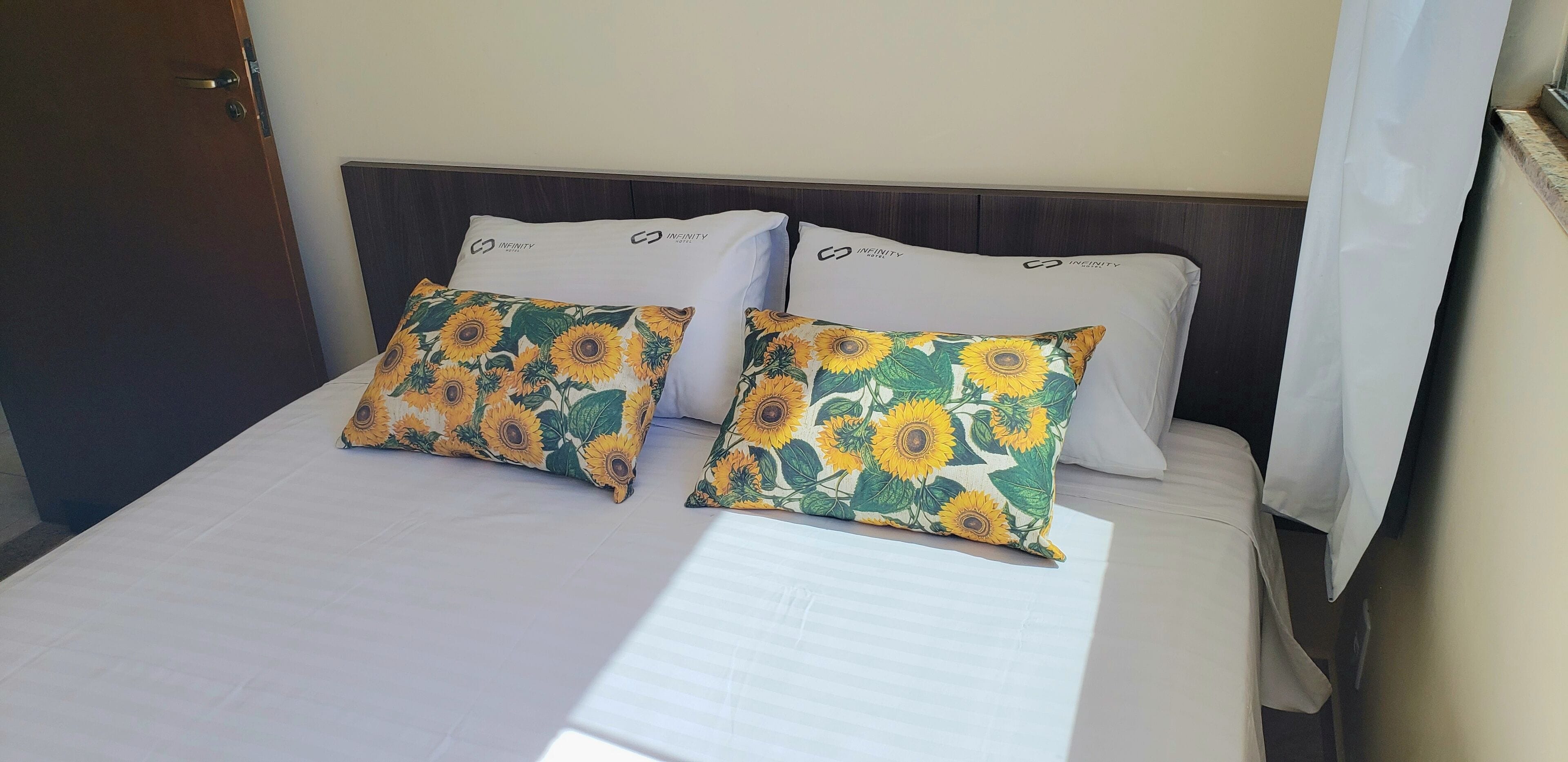 Un letto con due cuscini, uno decorato con un motivo a girasole e l'altro semplice.