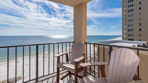Un balcón con dos sillas Adirondack con vistas a una playa y al océano.
