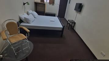 A room with a bed, a wheelchair, a small table, and a television.