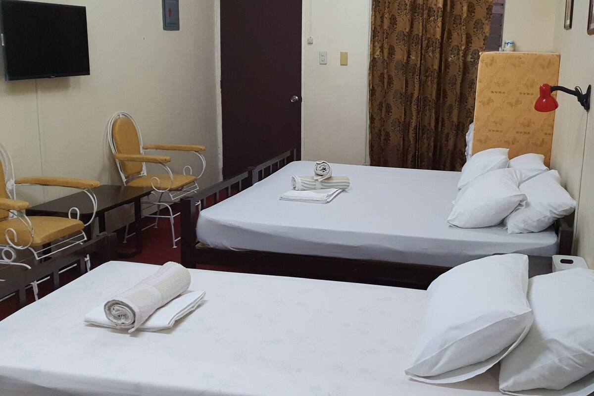 Habitación de hotel con dos camas, un escritorio y una silla.
