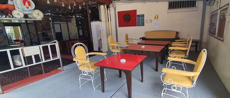 A small, cozy cafe with a red table and yellow chairs, a dartboard, and a sign for wheelchair access.