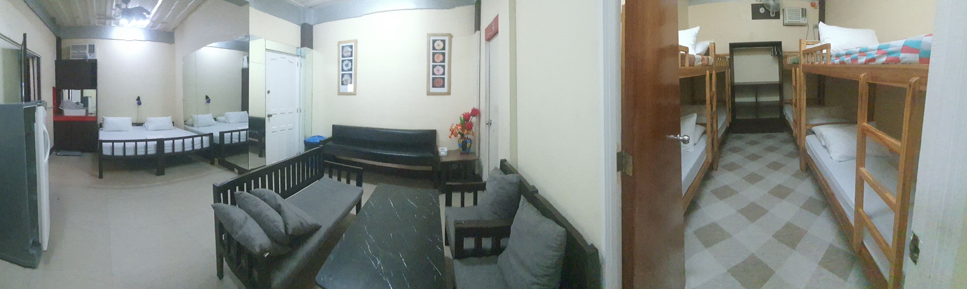 A room with bunk beds, a sofa, and a small table with a vase.