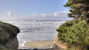 A coastal landscape with a rocky beach, cliffs, and ocean waves. - Zen Beach Retreat-Relaxing Sauna - Steps to a Sandy Beach! (Yachats)