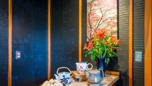 A wooden table with a vase of flowers, a teapot, a pitcher, and a plate of pastries. - Zen Beach Retreat-Relaxing Sauna - Steps to a Sandy Beach! (Yachats)