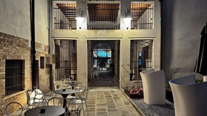 An outdoor café with tables and chairs, a brick wall, and a wooden ceiling. - Hotel Aquarius Venice (Venice)