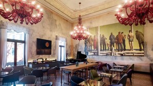 A dining area with a large mural, a grand chandelier, and a piano. - Hotel Aquarius Venice (Venice)