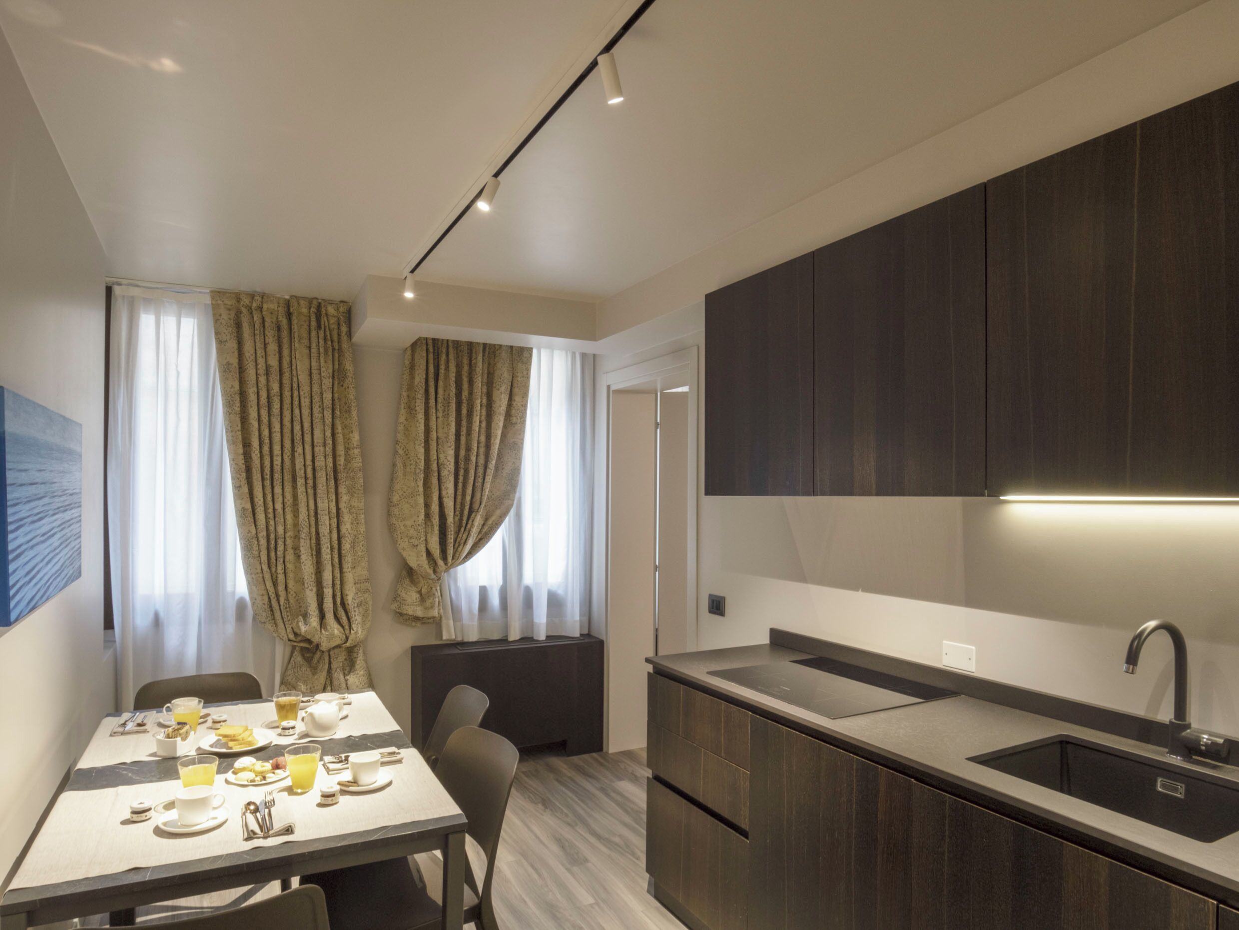A modern kitchen with dark wood cabinets, a built-in sink, and a dining area with a table set for breakfast.
