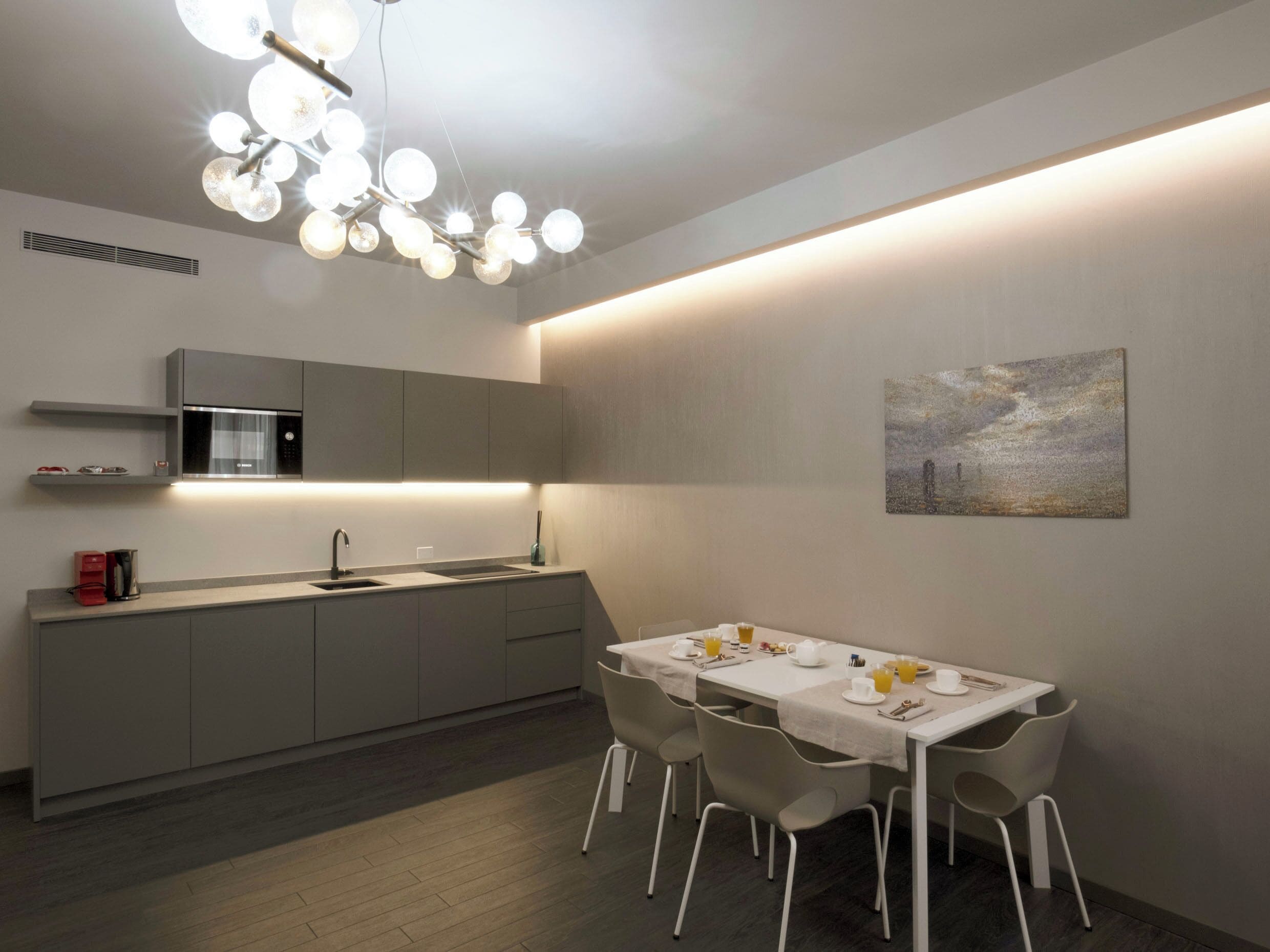 Una cocina moderna con comedor, que cuenta con una isla central, horno empotrado y lámpara colgante.