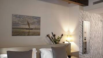 Une chambre d’hôtel comprenant un lit, une table de chevet, une lampe, un miroir et un mur orné d’un motif texturé.