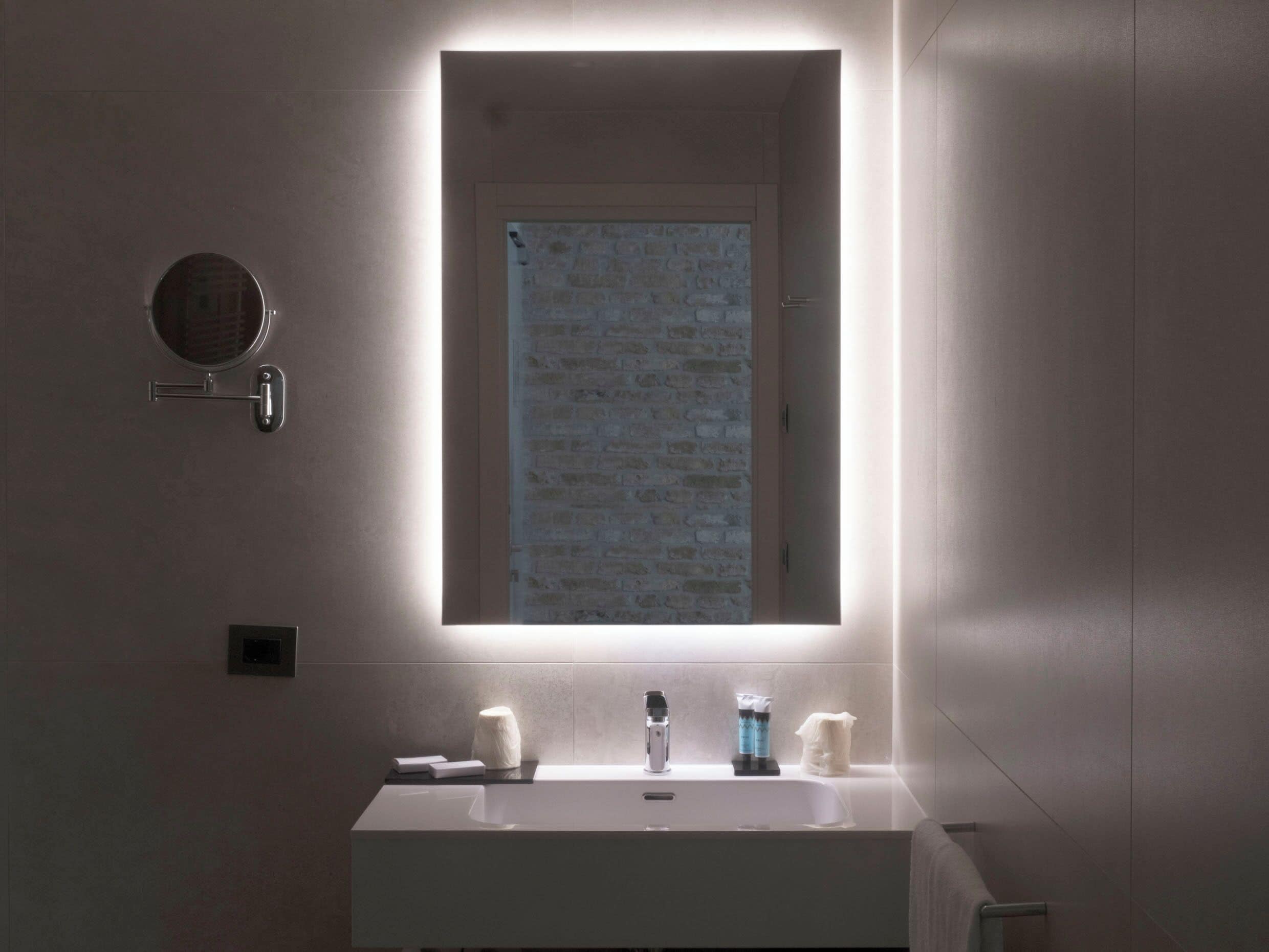 Une salle de bain moderne avec un miroir rectangulaire, un lavabo blanc et un porte-serviettes.