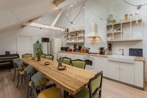 Une cuisine spacieuse avec une table à manger en bois, des chaises et un piano.