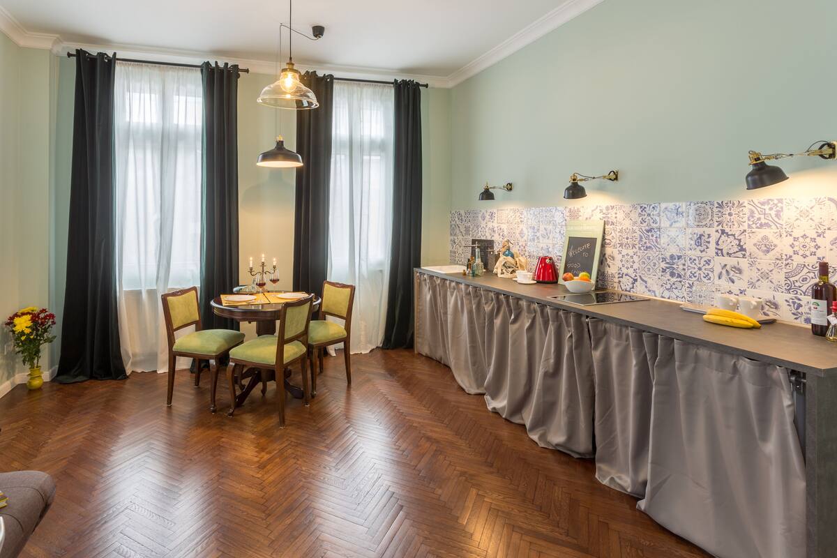A dining area with a round table, chairs, and a bar counter with a tiled backsplash.