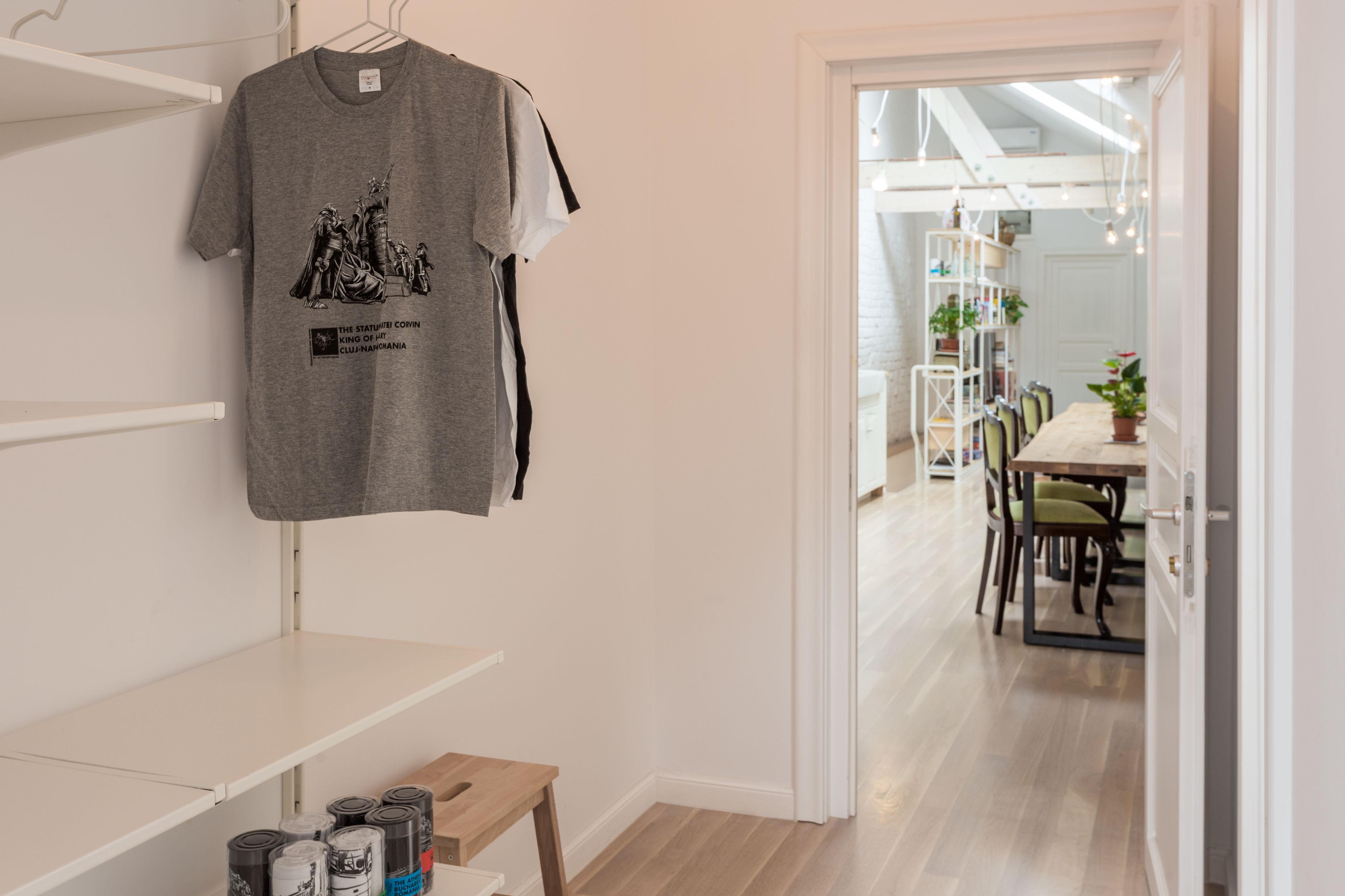 Una habitación con una camiseta colgada, una mesa de madera y un acceso a un comedor con sillas y una mesa.
