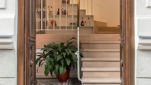 Un escalier menant à un palier agrémenté d’une plante en pot et d’un luminaire suspendu.