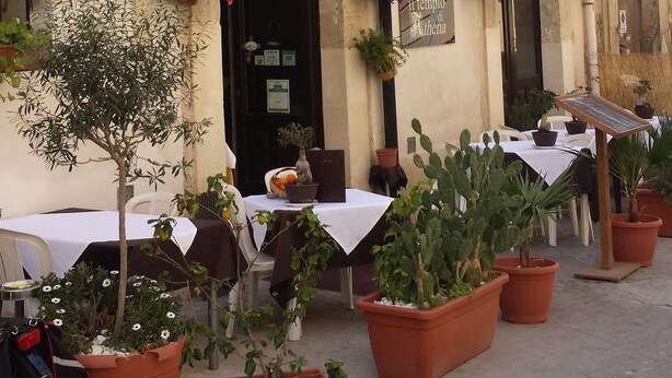 A building with outdoor seating, potted plants, and a sign for 'Il Tempio di Athena'. - Casa Aretusa (Syracuse)