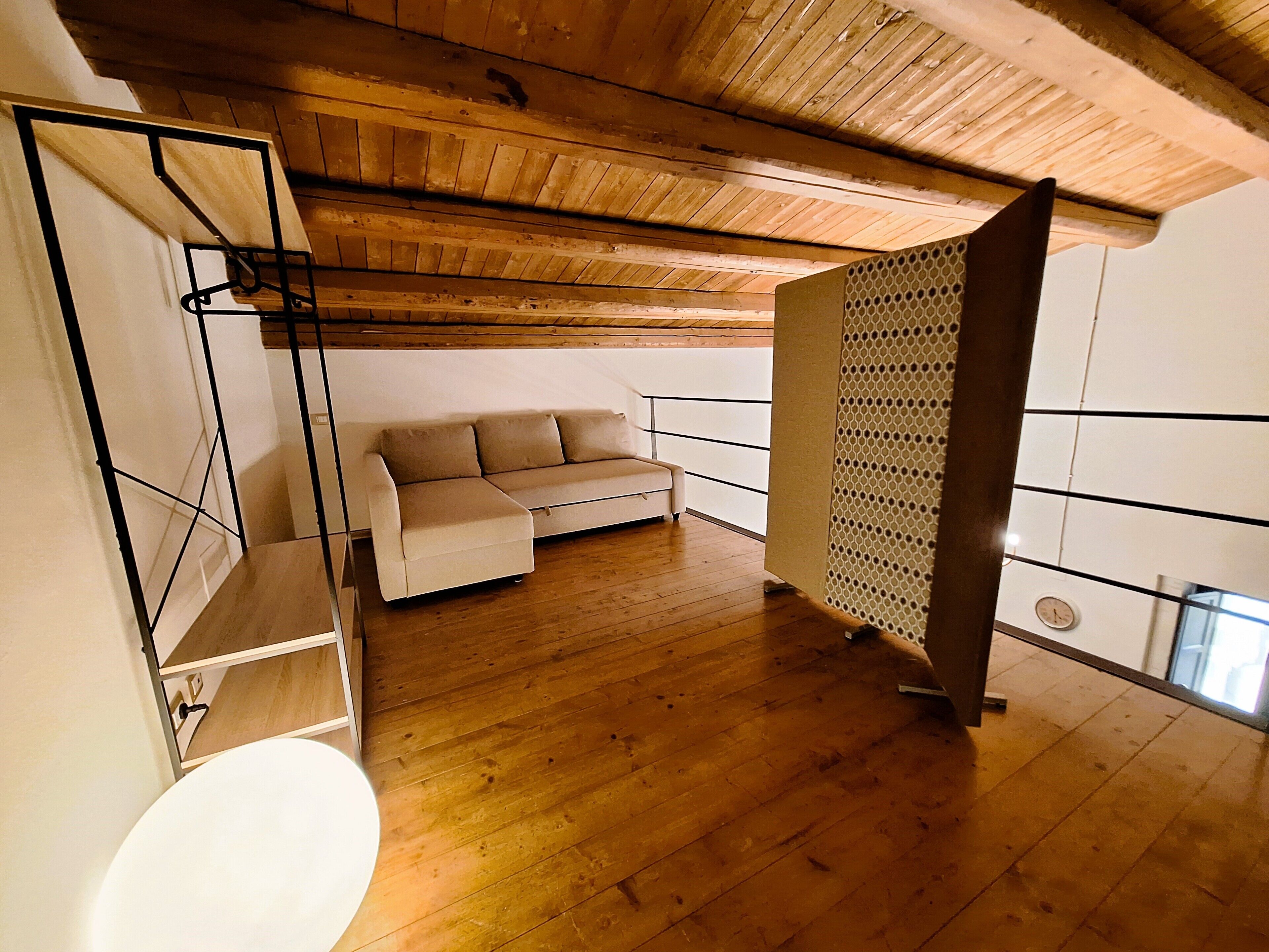 Una habitación con techo de madera, un sofá blanco, un armario blanco y una bañera blanca.