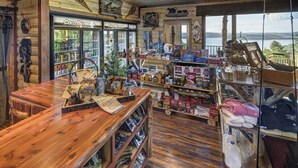 A rustic interior with wooden shelves stocked with various products, a wooden bar, and a view of the outdoors. - Lake Shore Cabins on the Waterfront of Beaver Lake with Boat Dock & Swim Deck (Eureka Springs,)