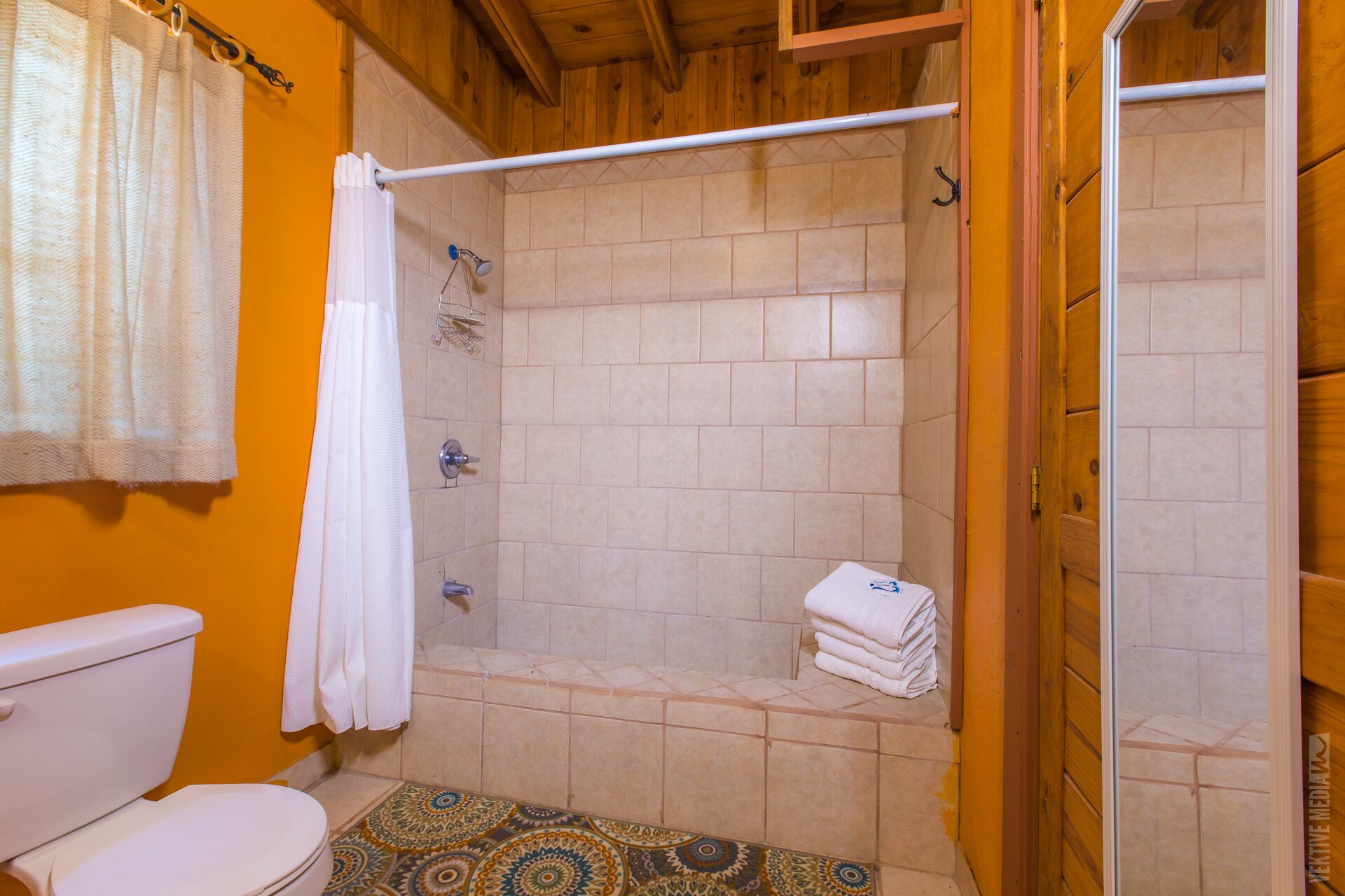 A bathroom with a shower, toilet, and a patterned floor.