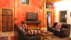 Un salon avec deux canapés en cuir, une table basse en bois et un téléviseur posé sur un meuble.