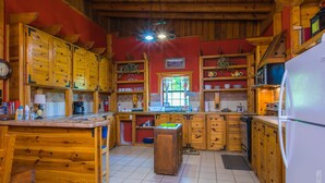 Une cuisine rustique avec des meubles en bois, un îlot central et un réfrigérateur.