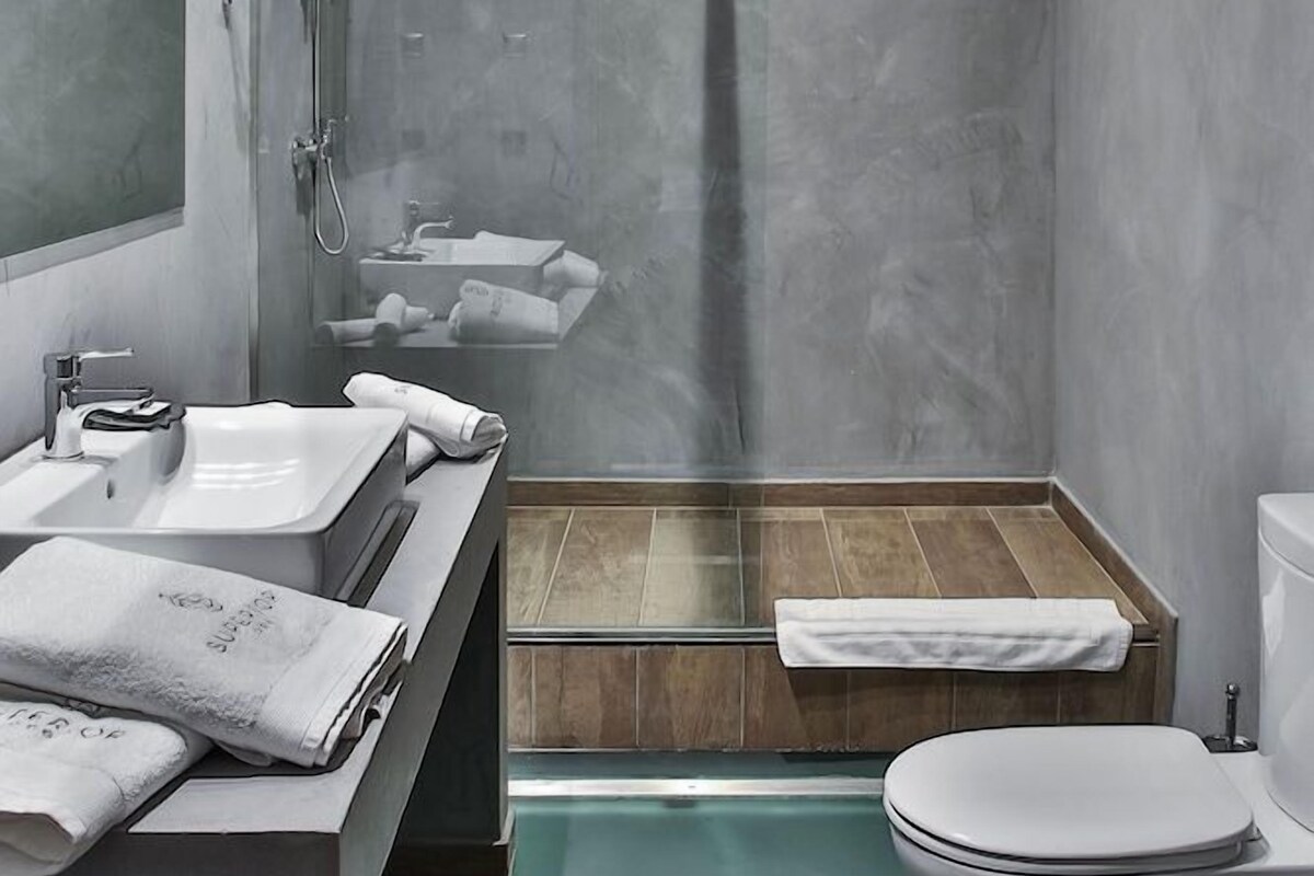 A modern bathroom with a glass-enclosed shower, a sink with a mirror, a toilet, and a wooden vanity.