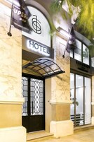 Fachada de hotel de mármol, con un amplio arco de entrada y un letrero que dice 'HOTEL'.
