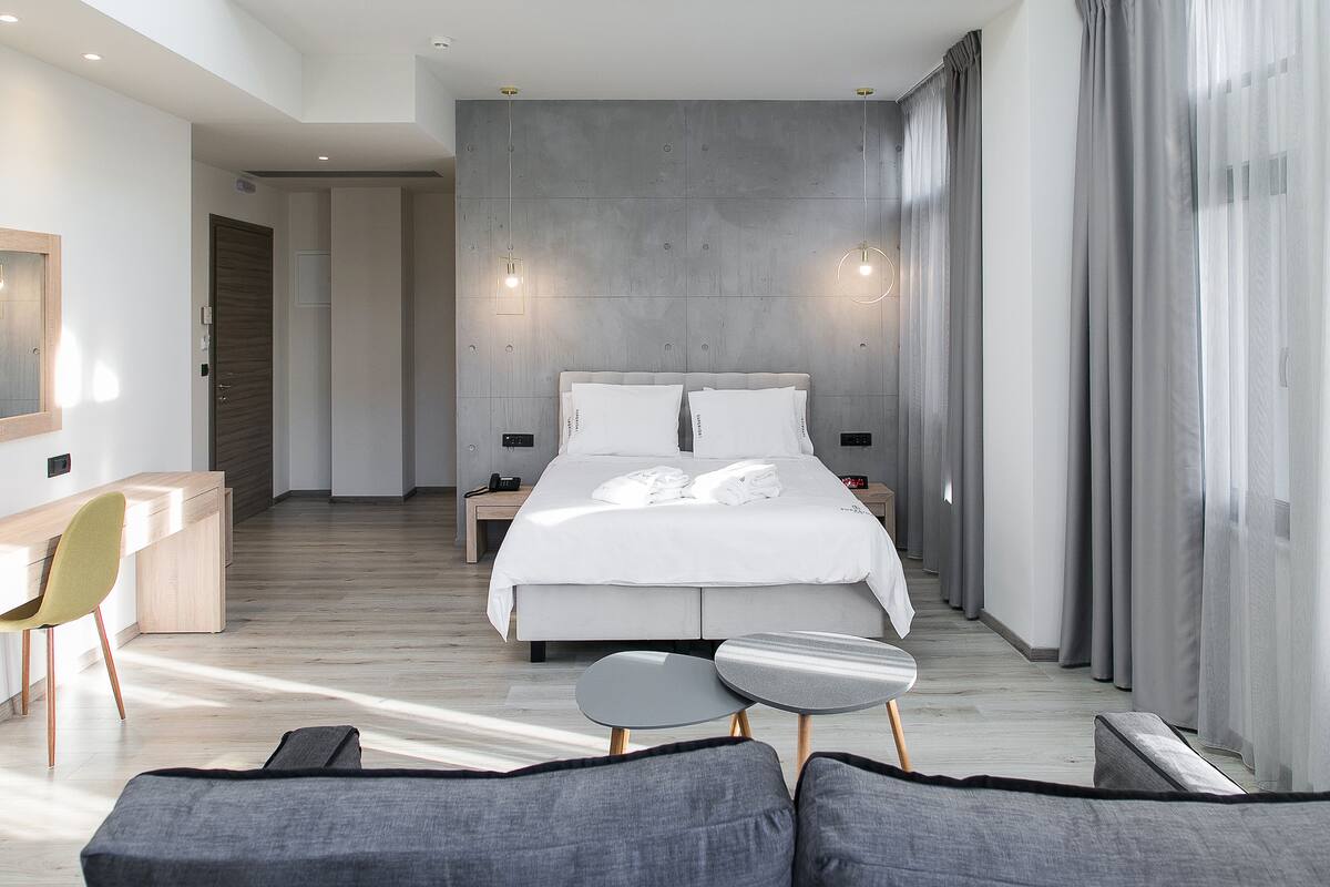 Une chambre d’hôtel moderne dotée d’un grand lit, de tables de chevet, d’un bureau et d’un coin salon.