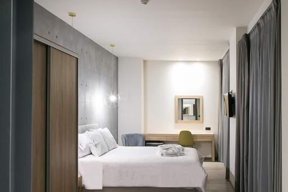 Une chambre d’hôtel moderne avec un grand lit, un bureau et un miroir.