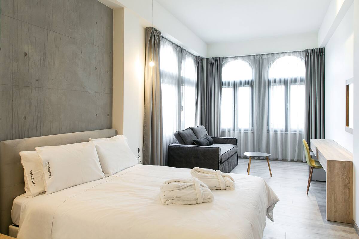 Une chambre d’hôtel moderne équipée d’un grand lit, d’un bureau, d’une chaise et d’un canapé.