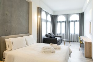 Una habitación de hotel moderna con una cama grande, un escritorio, una silla y un sofá.