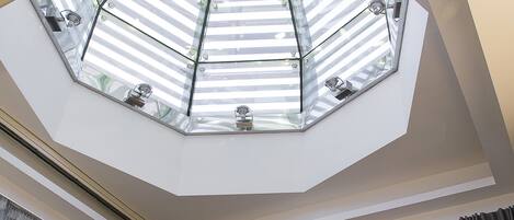Una sala de estar moderna con un televisor de pantalla plana grande, un sofá de color oscuro y un techo skylight.
