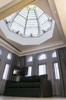 Ein modernes Wohnzimmer mit großem Flachbildfernseher, einem dunkelgrauen Sofa und einer Dachfensterdecke.