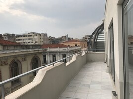 Un balcón con vistas a edificios circundantes y un cielo despejado.