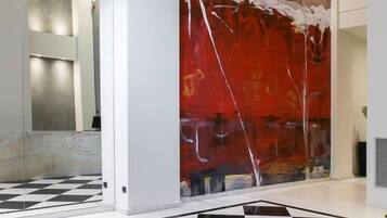 A lobby with a checkered floor, a large abstract painting, and a glass partition.