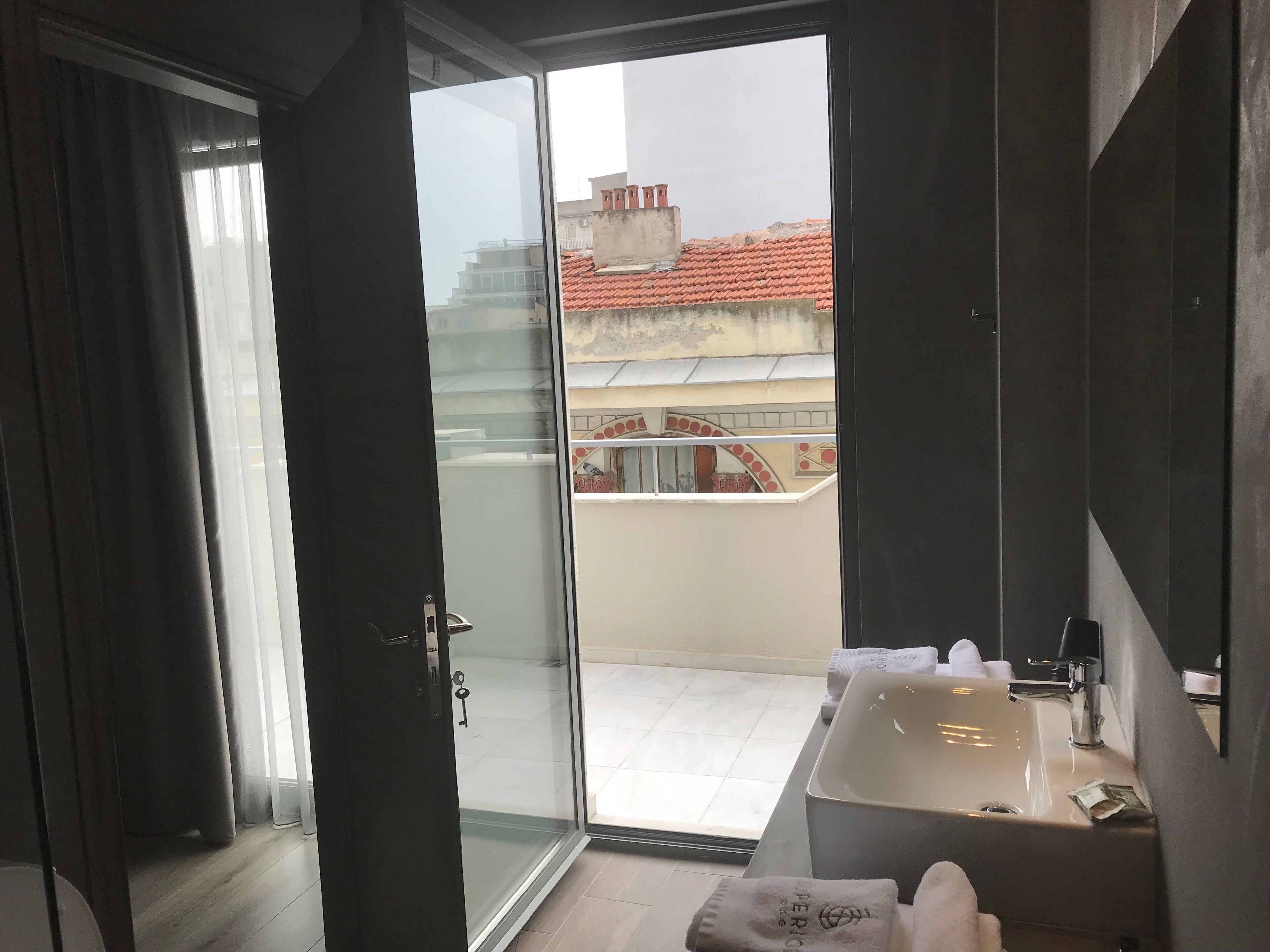 A modern bathroom with a glass door leading to a balcony, a sink, and a towel.
