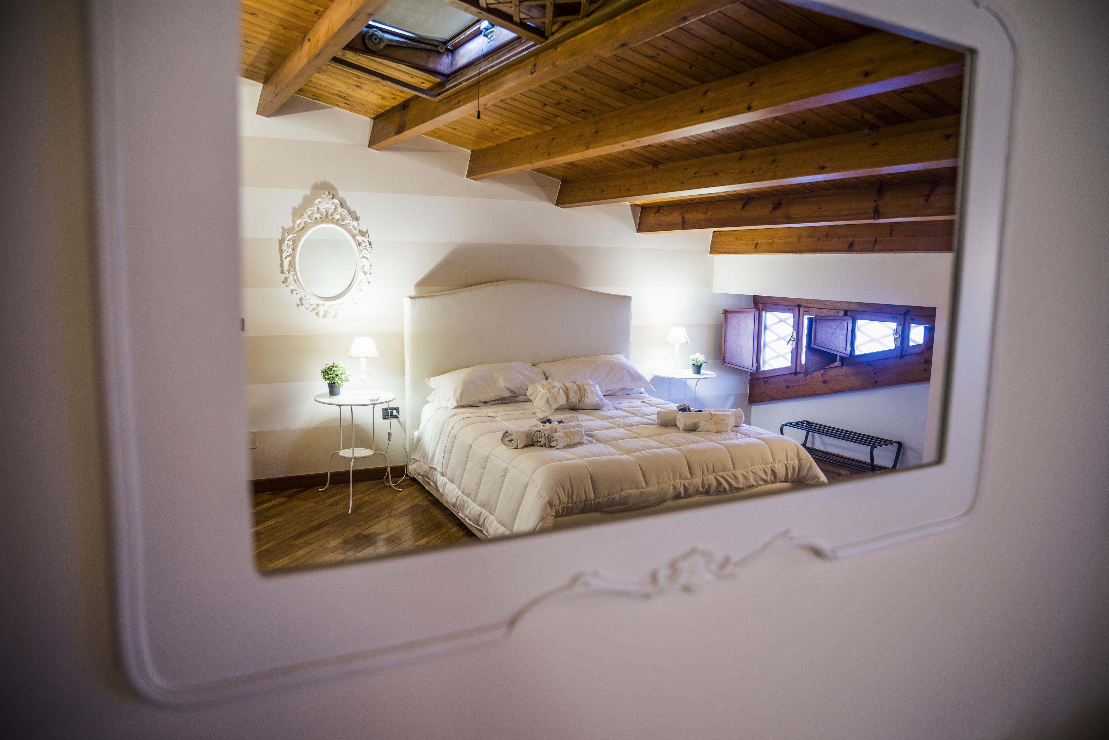 Une chambre à coucher avec un grand lit, des lampes de chevet, une petite table avec une plante et un miroir au mur.