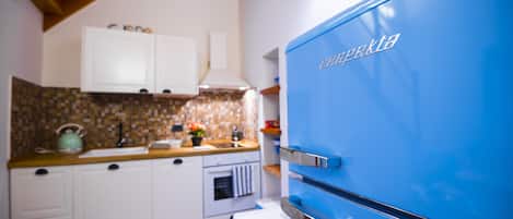 Een keuken met witte kastjes, een blauwe koelkast en een betegelde spatwand.