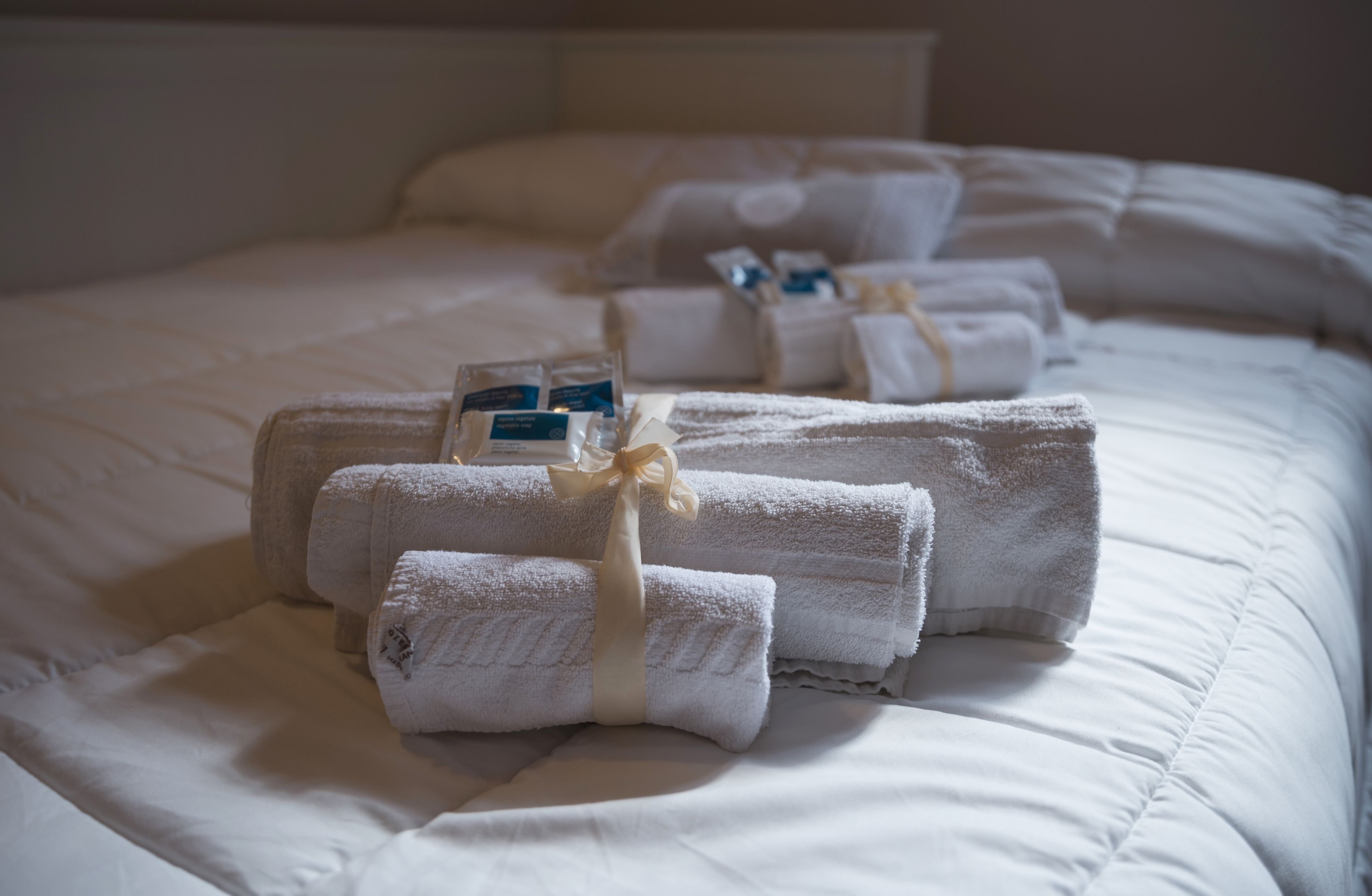 A neatly made bed with folded white towels and toiletries.