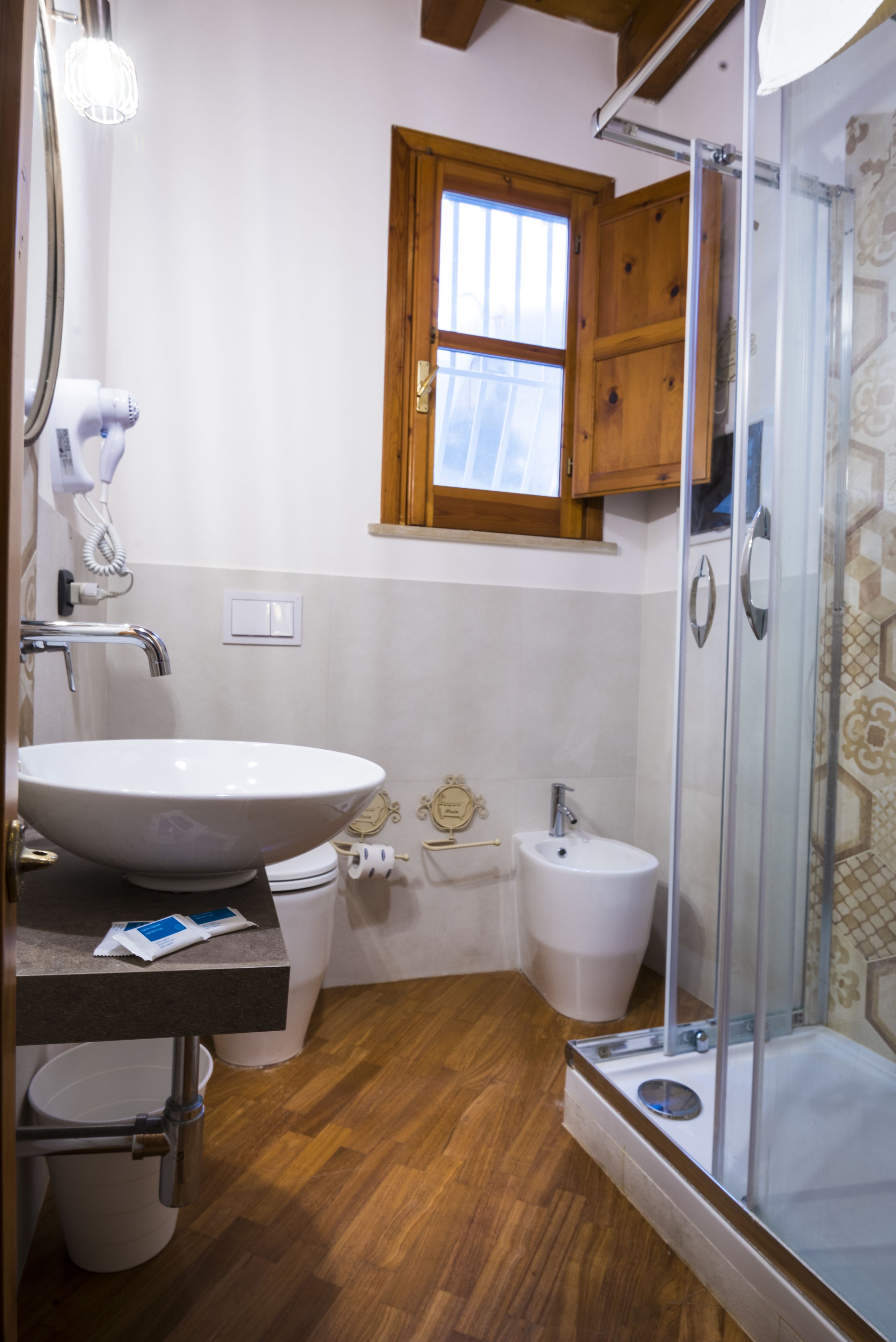 Ein Badezimmer mit einem großen Waschbecken, einer Toilette, einem Bidet und einer Duschkabine.