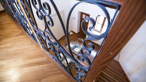 Un escalier en bois avec des rampes en métal noir à motifs décoratifs.