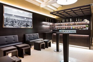 A modern bar area with a large framed black and white photo, leather seating, and a variety of liquor bottles.