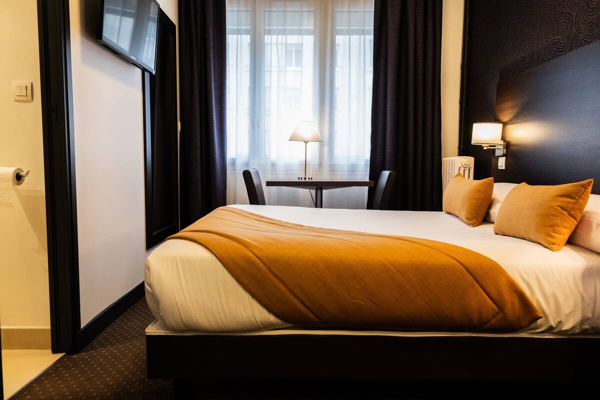 A hotel room with a bed, a table, and a chair.