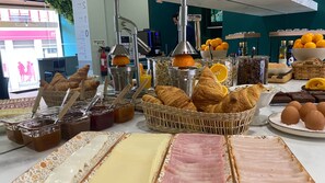 A breakfast buffet with croissants, jams, eggs, and orange slices. - Hotel Santiago Vagos (Vagos)